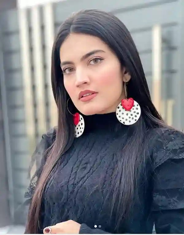 Woman wearing black sweater and red heart earrings with polka dot patterns. (Verified reviewer)